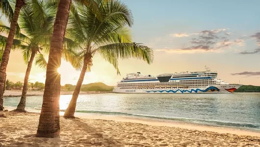 AIDAluna in der Karibik mit Palmen am Strand